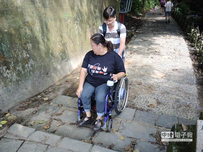 虎山溪步道入口有2階石階，輪椅族需由另一人協助，才能順利進入步道。（張潼攝）