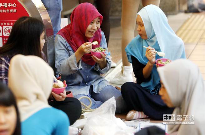 他们三五成群坐在车站大厅开心地与同乡品嚐着家乡口味美食，聊以稍解思乡之情。（陈志源摄）