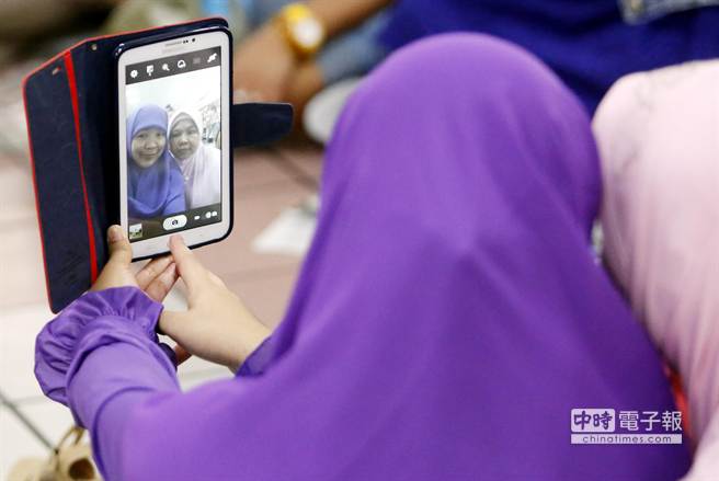 她们穿着传统服饰开心地与同乡合影留念。（陈志源摄）