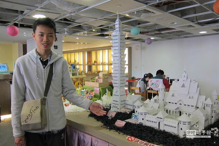 小崴與在草悟廣場文創館展出的紙雕創作--「冰雪奇緣」和「101大樓」合影。（陳世宗攝）