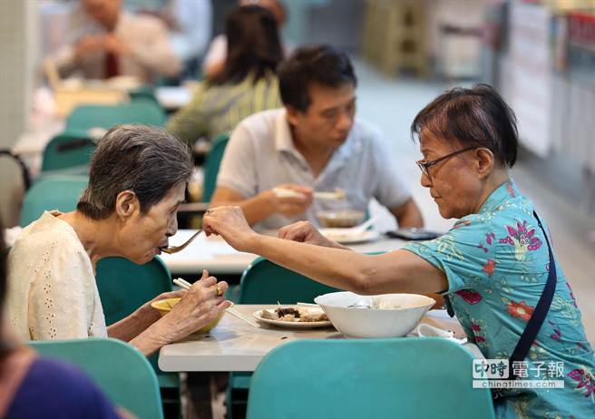 晚餐時刻，1對高齡母女24日在龍山商場小吃店享用簡單麵食配小菜，年逾70的女兒正餵高齡93歲的母親喝湯，平淡晚餐流露母女溫馨情。（王錦河攝）