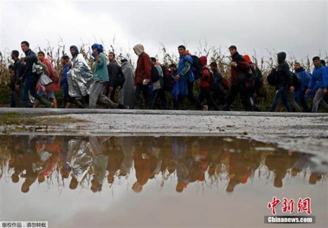 當地時間10月20日，在斯洛維尼亞與克羅埃西亞邊境城市多波瓦，斯洛維尼亞全副武裝的軍警「護送」從克羅埃西亞入境的難民。(摘自中新網)