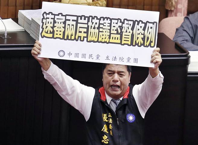 2015年9月15日台北市/立法院15日处理变更议程案表决时，立委张庆忠突然爬上主席台前的桌子举起标语，跪求速审两岸协议监督条例。（本报系资料照／姚志平摄）