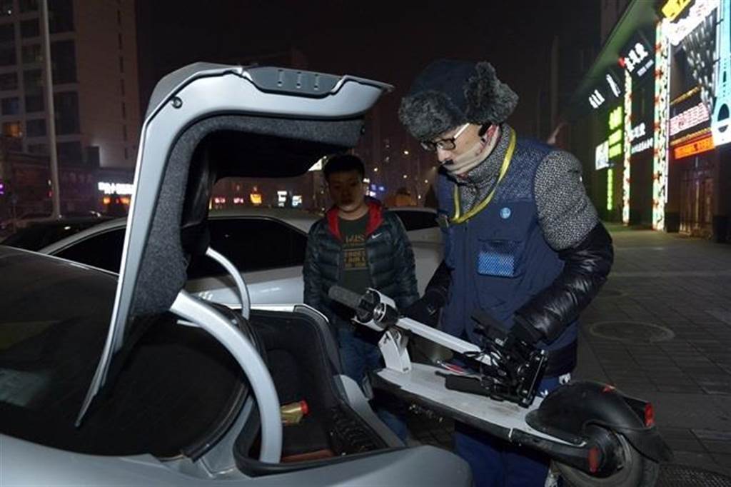 12月22日，余桥把电动滑板车放入顾客车辆的后备箱，准备送顾客回家。（新华社）
