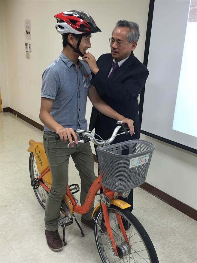 前衛福部長、北醫大講座教授邱文達（右），示範正確戴自行車安全帽。（廖珮妤攝）