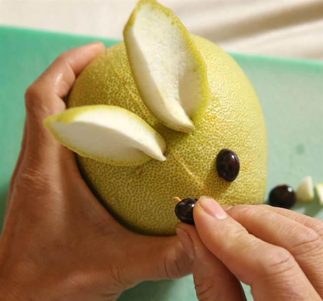 簡單九步驟雕兔子之7.將牙籤與龍眼核插進柚子中。（王英豪攝）