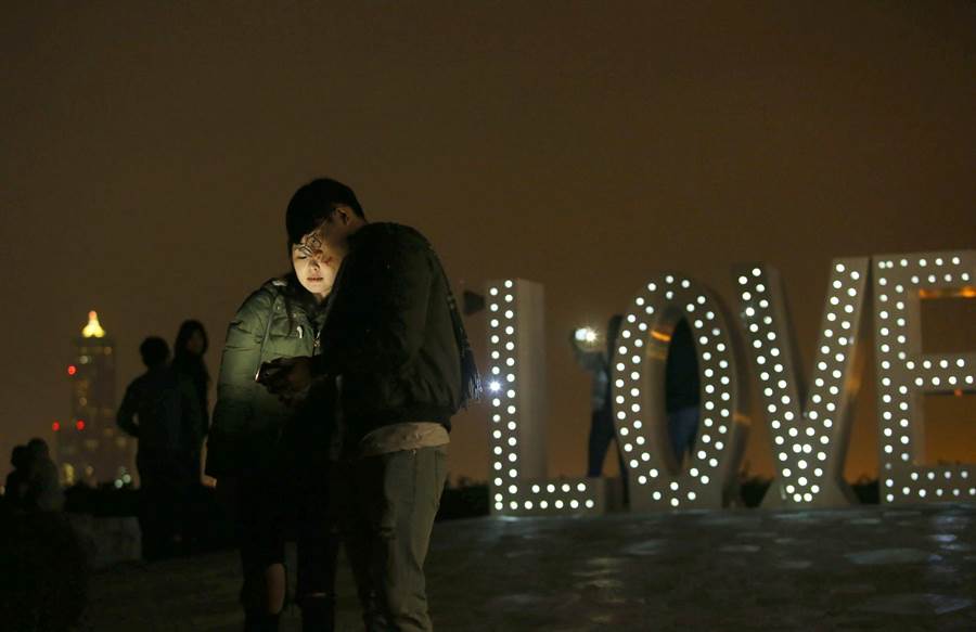 不少情侶14日晚間在高雄壽山 LOVE 地標前自拍留念，共度情人節。（王錦河攝）