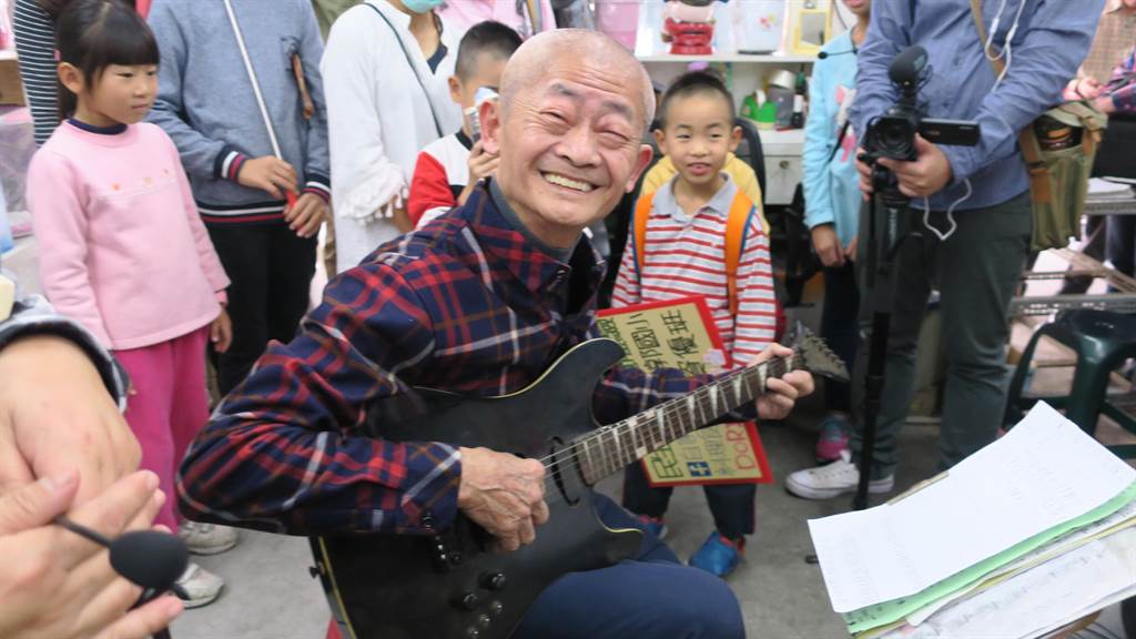 市場裡人稱太郎阿公的78歲的電器行老闆張榮吉，滿臉笑容在店內為參觀市場小旅行的大小朋友彈奏電吉他，引來讚嘆。（謝瓊雲攝）