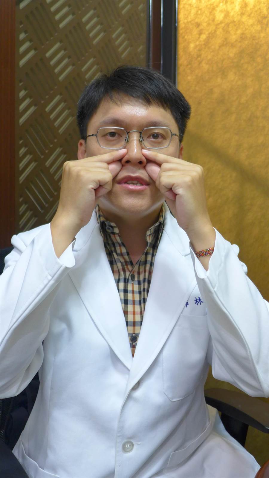 中醫師林育誠示範按摩鼻子兩側的迎香、合谷等穴位，幫助鼻子暢通。（林欣儀攝）