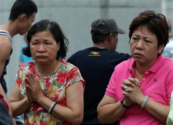 兩位女子（如圖）在火場大樓旁祈禱受困工人平安脫困。（王錦河攝）