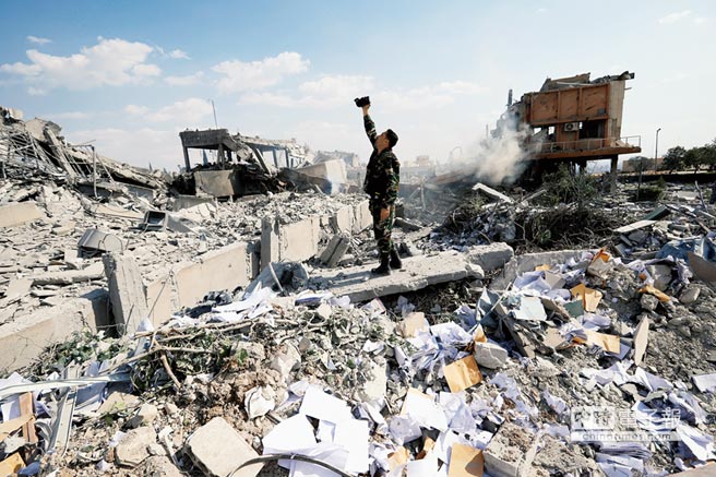 一名敘利亞士兵在大馬士革附近巴爾澤市被炸毀的「敘利亞科學研究中心」廢墟中查看並進行拍攝。美軍宣稱他們攻擊的是化武研究中心。（美聯社）
