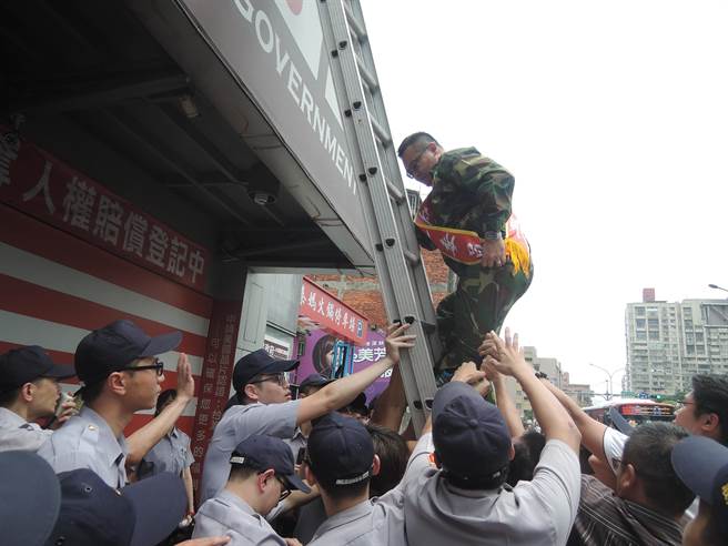 大陳島文化促進會理事長胡志偉朝爬上鋁梯去圖拆除招牌。（王揚傑攝）