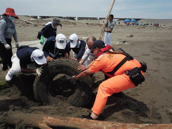 大家同心協力淨灘，終於挖出巨大輪胎。（陳淑娥翻攝）