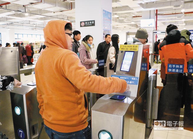 1月26日，在廣西柳州市火車站乘車的民眾，持二代身分證和車票通過人臉識別系統進站。（中新社）