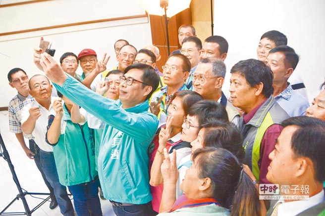 国民党高雄市长参选人韩国瑜以「把马子不分人种」抨击对手陈其迈观光「不该偏重陆客」之说，陈其迈昨未回应。图为陈日前与党籍提名里长合拍宣传照前先拿起手机自拍。（本报资料照片）