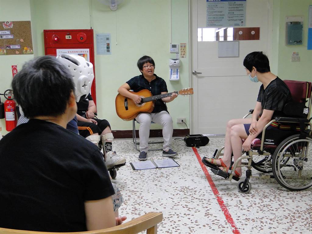 花蓮黎明教養院音樂治療師陳綺慧彈吉他教唱，引起心智障礙院生共鳴。（范振和攝）
