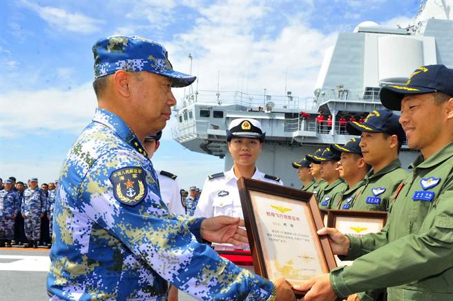 大陆的舰载机飞行员驾驶歼—15舰载机在辽寧舰上成功进行阻拦着舰和滑跃起飞，通过航母飞行认证。图为舰载机飞行员完成辽寧号航母起降后获颁证书。（图／中新社）