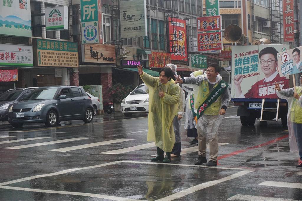 前行政院長賴清德（左）8日上午德穿著輕便雨衣，和民進黨台南市第二選區立委補選候選人郭國文在雨中街頭拉票