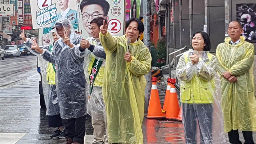 前行政院長賴清德（中）8日上午德穿著輕便雨衣，和民進黨台南市第二選區立委補選候選人郭國文在雨中街頭拉票