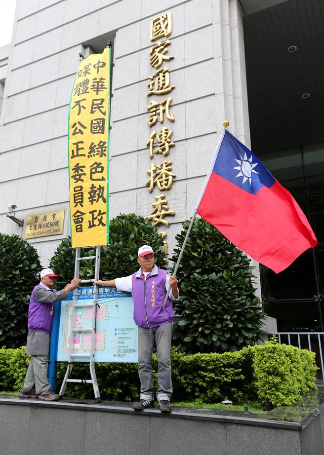 抗議成員在NCC招牌前立起一面「中華民國綠色執政媒體不公正委員會」，諷刺NCC面對媒體是雙重標準。（黃世麒攝）