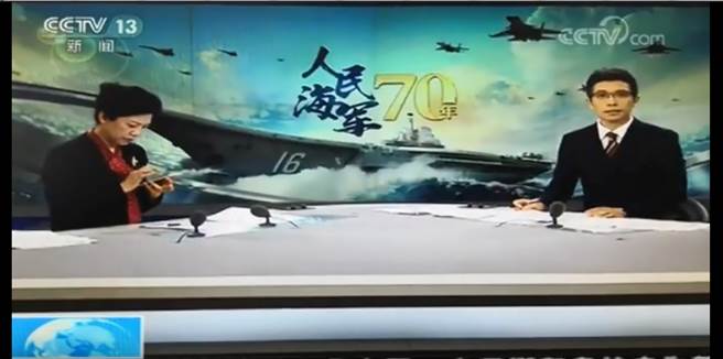 大陸央視在直播青島中共海軍檢閱儀式時，低頭滑手機的畫面不慎播了出去。（圖／網路視頻截圖）