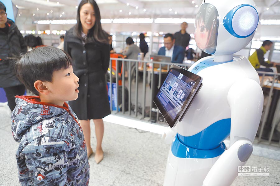 2月18日，大陸首個5G火車站在上海虹橋火車站啟建。圖為旅客在虹橋火車站體驗智慧機器人送餐。（中新社）