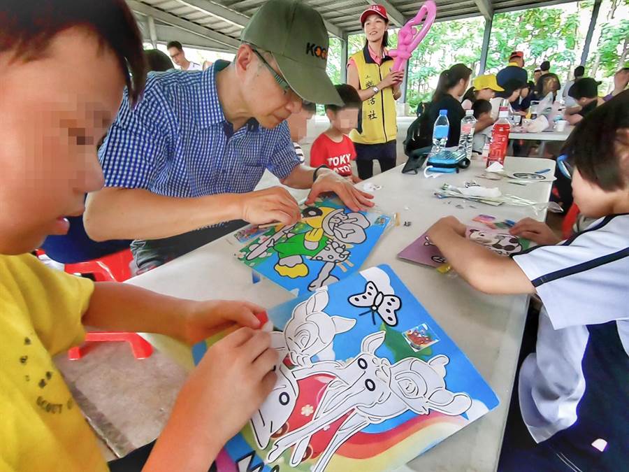 台灣大車隊執行長楊榮輝（左二）引導特教生家庭體驗沙畫創作的樂趣。圖：業者提供