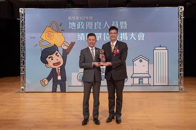 永庆不动产新竹科园加盟店店东陈绍庆(图右)获颁「新竹市优良地政士暨不动产经纪人」，从新竹市长林智坚(图左)手中接过奖杯。