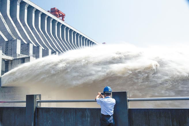 2018年7月，隨著持續強降雨，三峽大壩泄洪調整水位，一名工作人員用手機拍攝泄洪情況。（新華社資料照片）
