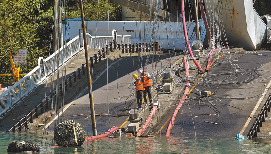 2名工程人員在倒塌的橋面上，仔細檢視斷裂的鋼索。（范揚光攝）