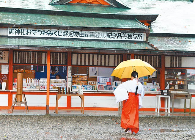 日本和歌山縣的熊野那智大社，神社的一名巫女在雨中行走。（新華社資料照片）