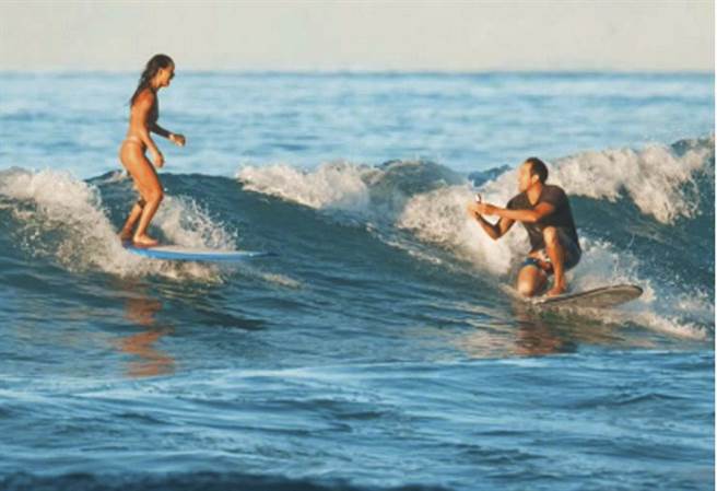 美國夏威夷男子賈司10日與愛人衝浪時，突然半跪在衝浪板上，拿出戒指求婚。(美聯社)