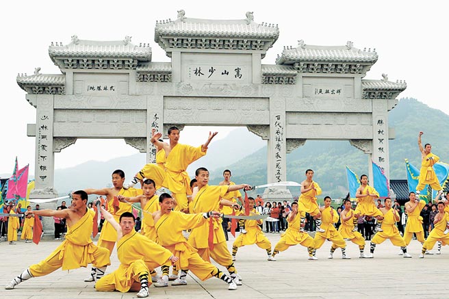 河南嵩山少林寺外的石牌樓前，一群武校學員表演少林功夫。（新華社）