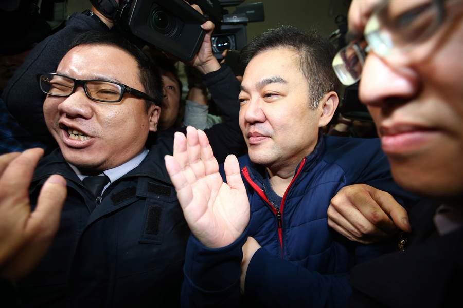 遠東航空12日無預警宣布停飛，北檢13日晚間以被告身分傳喚董事長張綱維說明，張綱維（中）到台北地檢說明，遭到大批媒體包圍，為他開道的法警也擠到面露痛苦表情。（陳信翰攝）