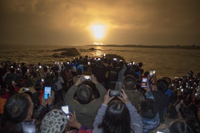 大陆长征5号火箭在时隔两年多后的第3次发射。图为海南省文昌市龙楼镇淇水湾，民眾聚集观看长征5号火箭发射，纷纷拿起手机拍照。（图／中新社）