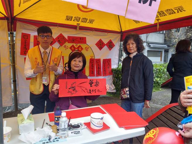 精忠里里长邀请黄宝贵邻长(图中)现场挥毫赠春联，黄邻长也是社区国画班的教师，春联作画吉利鼠祝大家鼠年行大运。