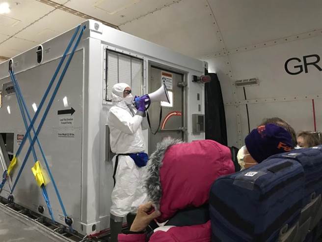 一名全副武装的防疫人员17日拿着扩音器，在包机上对撤离的「钻石公主」号美国乘客提醒注意事项。（路透）