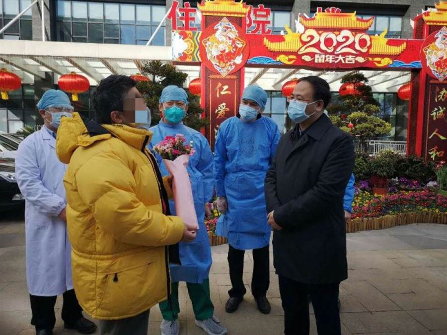 湖北省台辦主任李建紅(右一)在武漢協和醫院迎接痊癒出院的台商金先生(黃衣者）。(湖北省台辦提供)