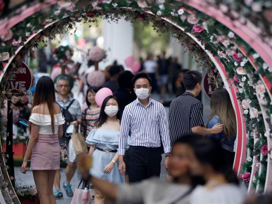 新加坡一對情侶14日戴口罩上街，慶祝情人節。（路透）