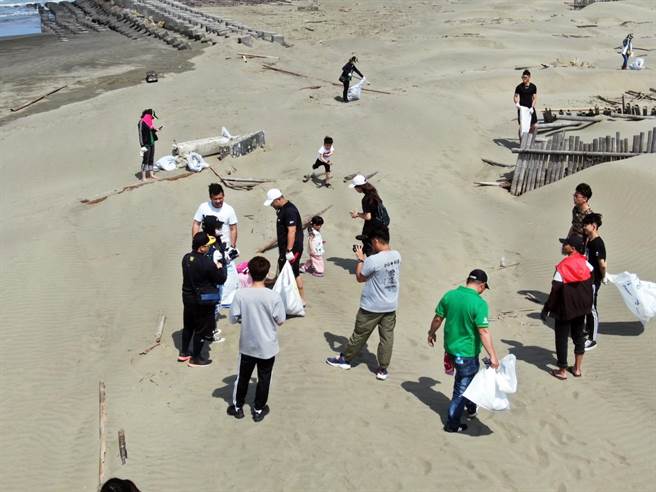 有人带着家中宝贝一起来净滩，希望孩子藉由亲手捡海洋垃圾的方式，了解垃圾如何破坏海洋生态。（有巢氏房屋提供／张毓翎嘉义传真）