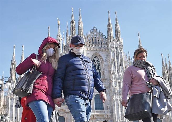 义大利疫情失控。图为民眾戴口罩走过米兰大教堂。（新华社）