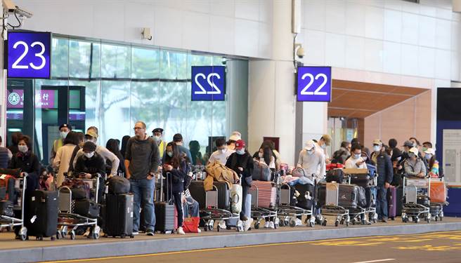 中央疫情指挥中心公告，自19日凌晨0时起，所有入境旅客须居家检疫14天，旅客无亲友接机，只能搭乘防疫计程车，桃园机场清晨起，排队搭乘防疫计程车的入境旅客排队人龙超过上百公尺，挤爆计程车排队区域，搭上车要等待近二小时，桃机防疫车队还请求松山机场车队支援。（陈麒全摄）