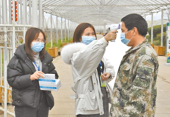 成都市一庄园工作人员，为进入园内工作的村民测量体温并发放口罩。（新华社）