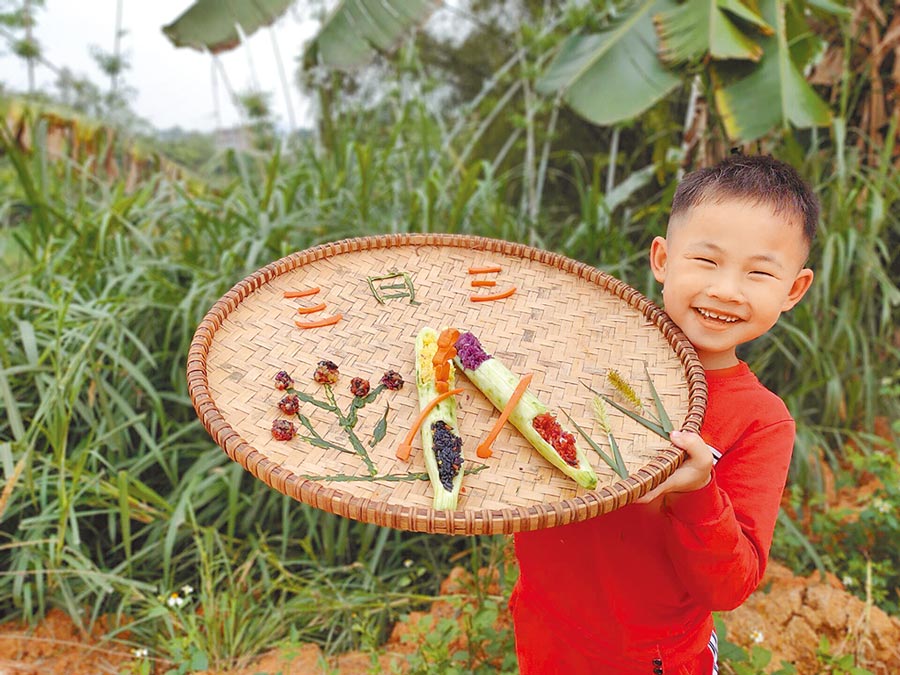 廣西南寧一名小學生在展示自製的五色糯米飯。（南寧市興寧區文化館供圖）