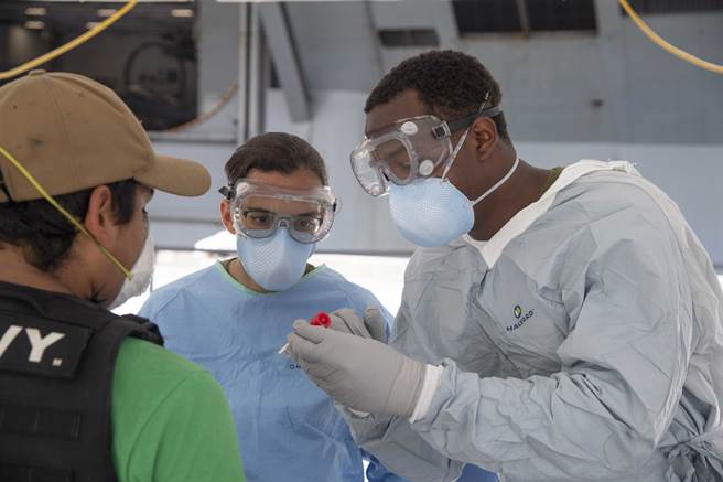軍方醫療人員4月20日在「羅斯福」號（USS Theodore Roosevelt，CVN-71）航母上為相關人員進行新冠肺炎採樣。（美國海軍）
