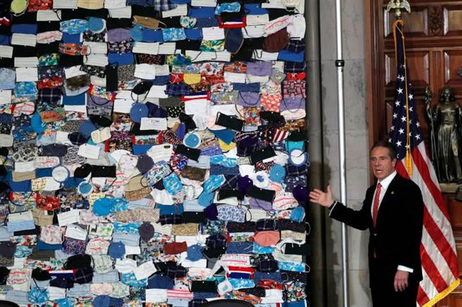 纽约州长科莫站在来自全国各地捐赠的自制口罩前，对外宣布一周内各地将陆续开放，并要求各地民眾配合防疫措施，以免疫情反弹。（图／路透）