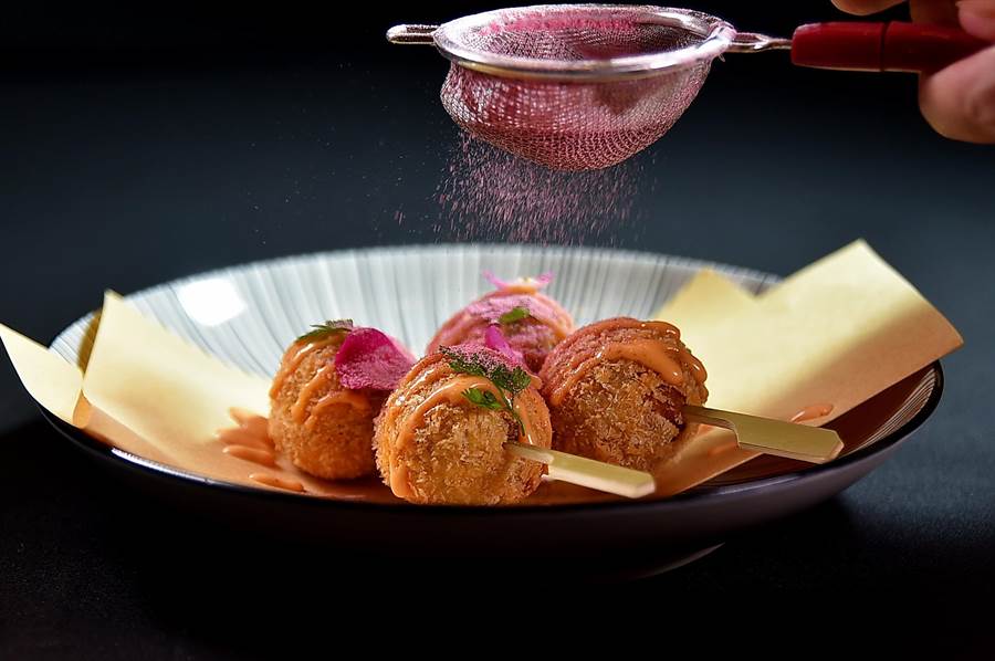 〈舊金山風味酥脆蟹肉球〉是以藍蟹肉拌入彩椒捏成球狀，裹麵衣炸至金黃，並灑上櫻花粉增色提味。（圖／姚舜）