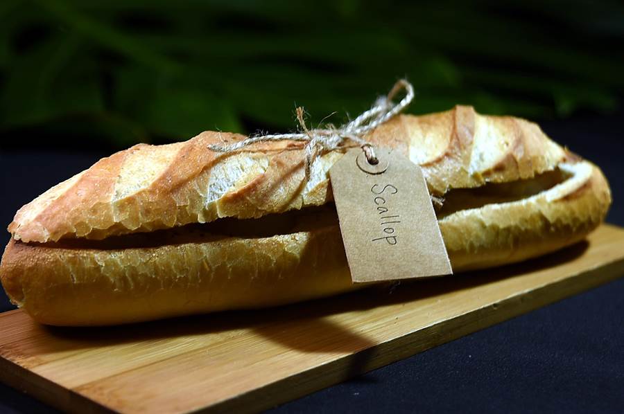 〈古法麵糰烤北海道大干貝〉是將干貝「鑲」在法式長棍麵包的麵團中烤製，外觀看不出「內涵」。（圖／姚舜）