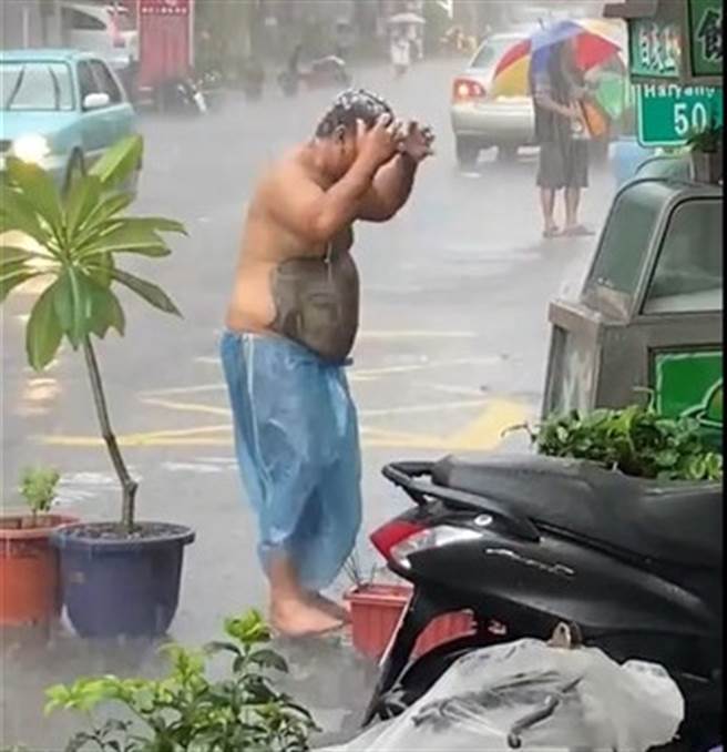 男子淡定在雨中洗头(图片取自/台湾新闻记者联盟)