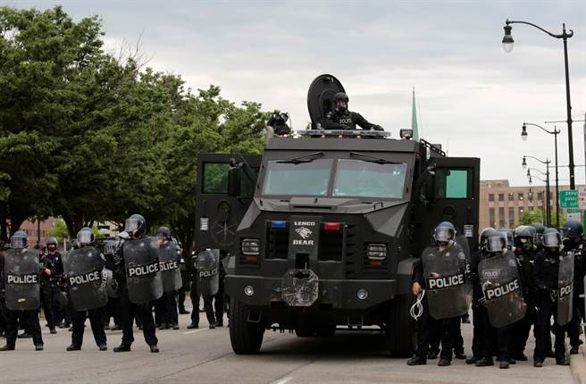 密西根州底特律警方1日身穿镇暴装备，在装甲车旁准备实施宵禁。（路透）